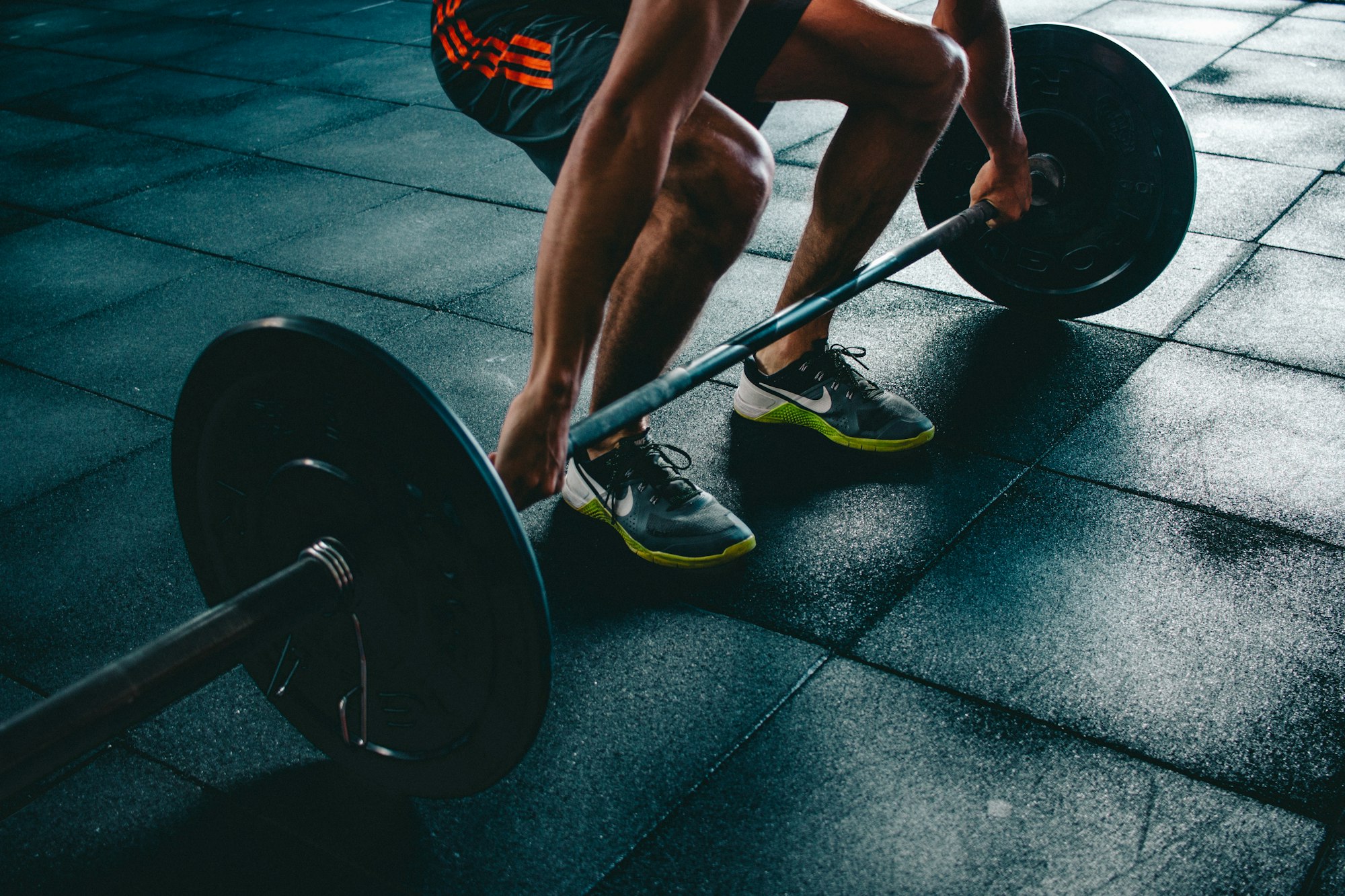 Person lifting a weight from the ground, a repetitive load that can strain tendons over time