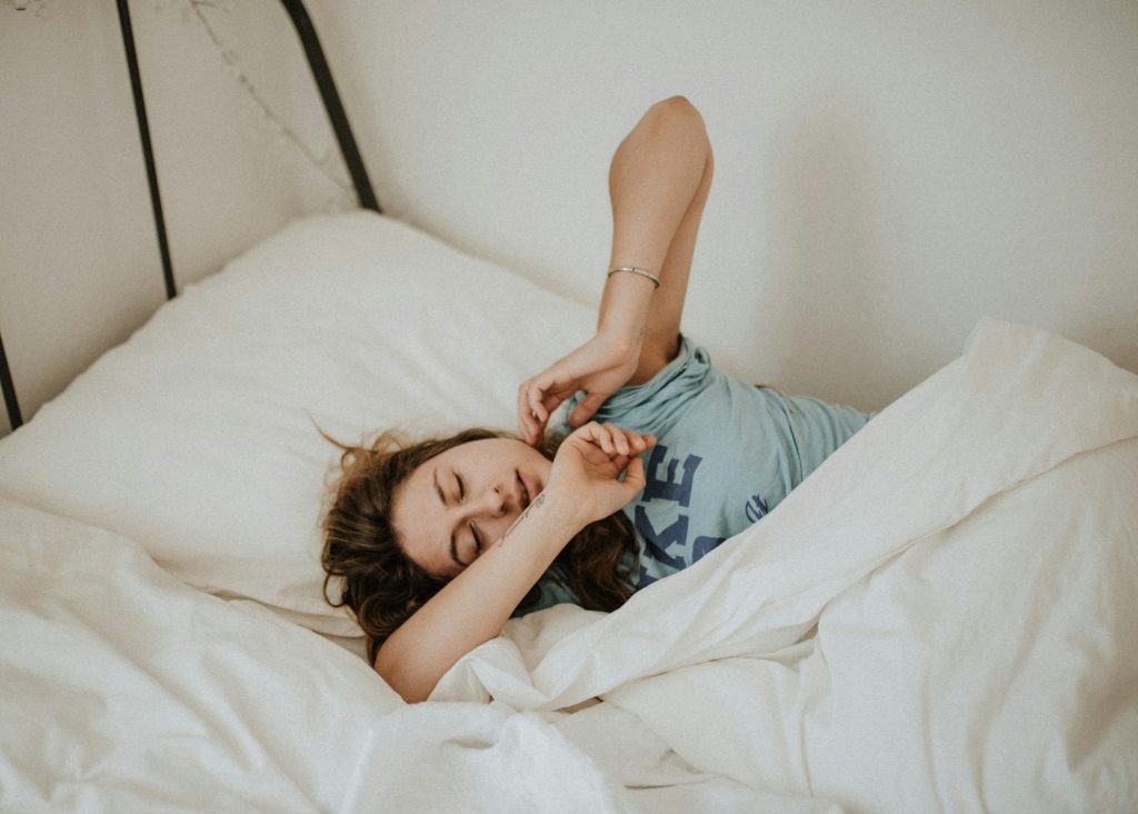 Person waking in the morning looking tired, sitting up in bed