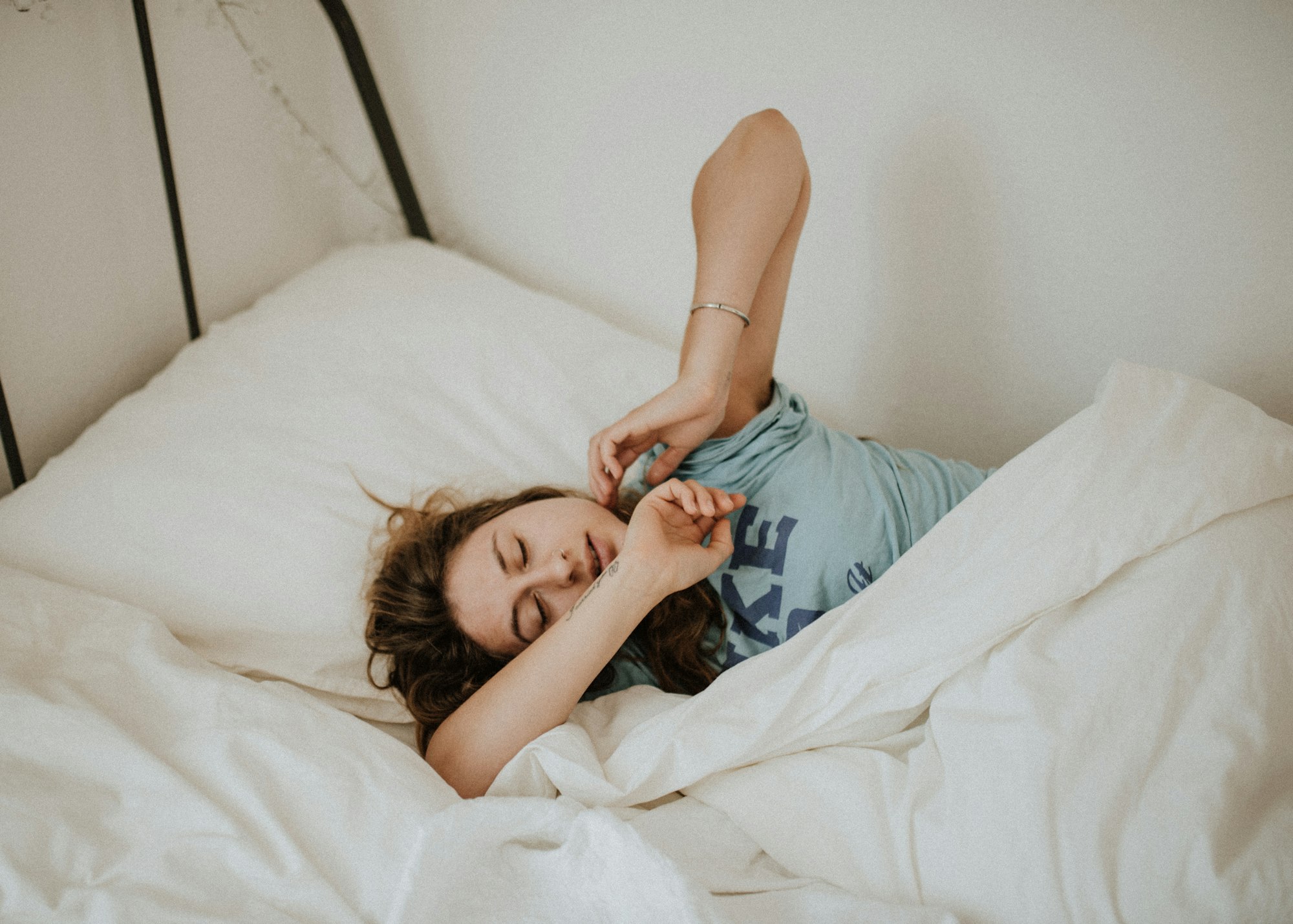 Person waking in the morning looking tired, sitting up in bed