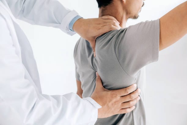 Massage therapist assessing a client's right shoulder by hand