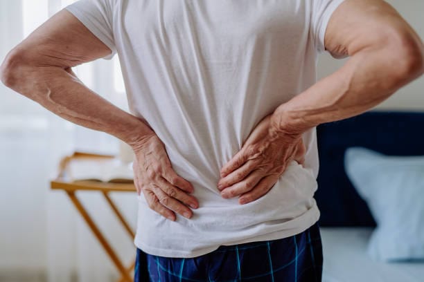 Man holding his lower back, where postural tightness is often felt first